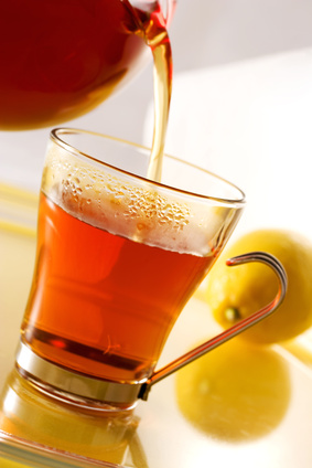 Aus einer Teekanne wird Tee in eine Tasse geschüttet