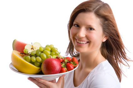 Junge Frau trägt Schüssel mit Obst