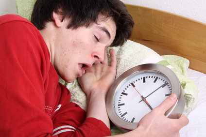 Jung im Bett mit einer Uhr