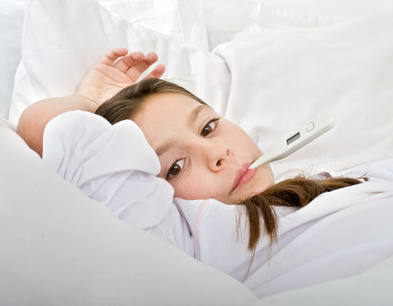Mädchen liegt mit Fieberthermometer im Bett