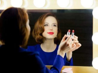 Frau schminkt sich am Hollywoodspiegel