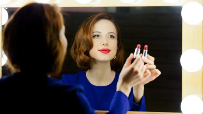 Frau schminkt sich am Hollywoodspiegel